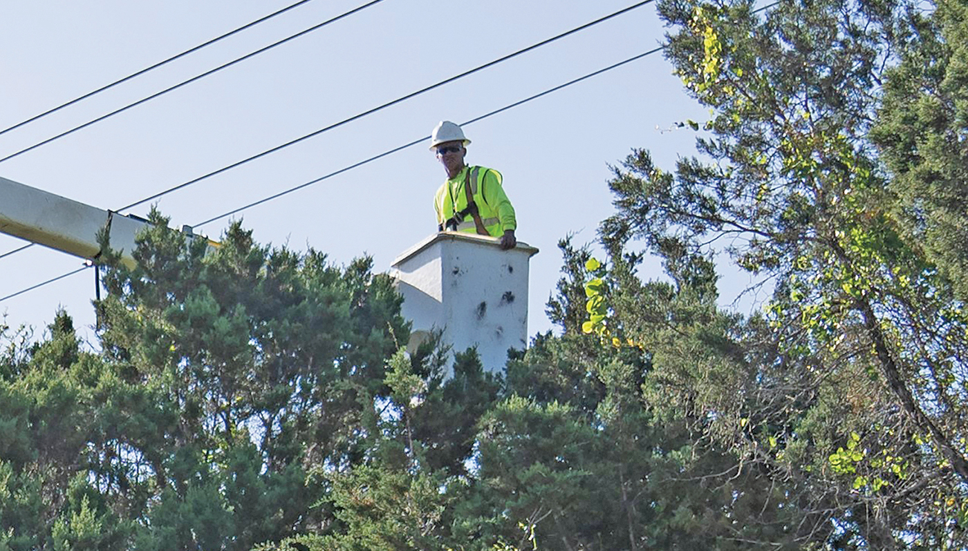 Photo of lineworker in bucket truck trimming trees under power lines