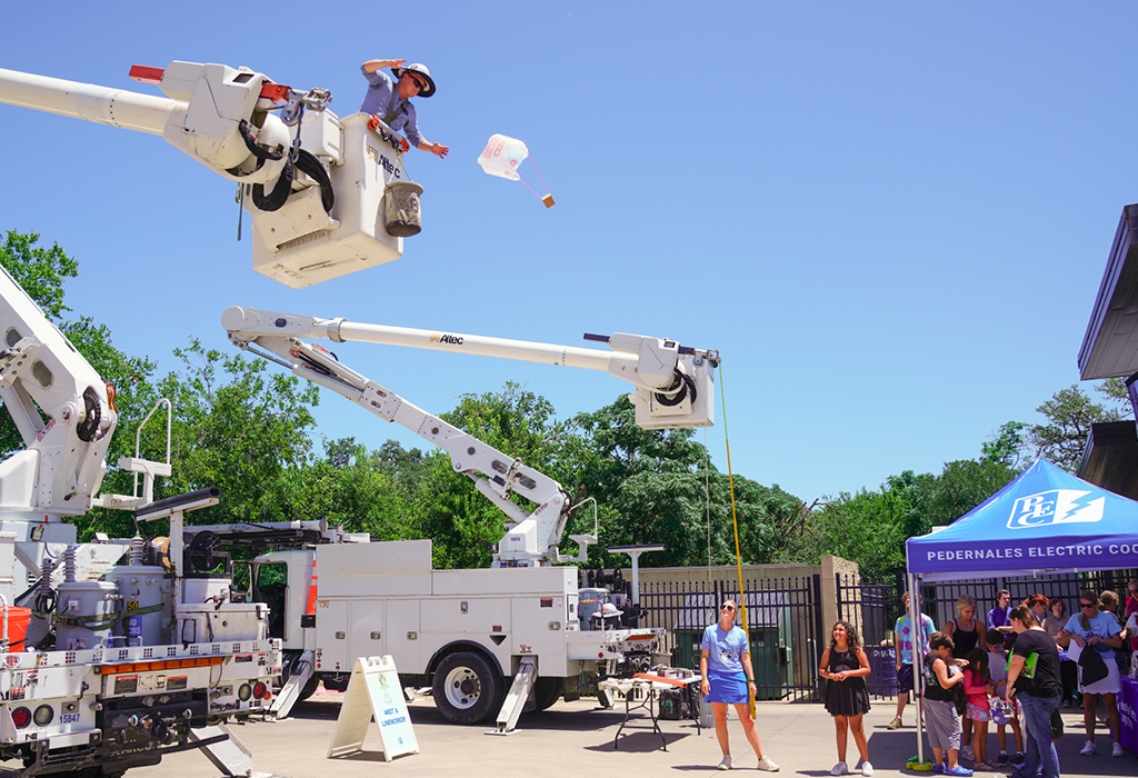 PEC lineworker dropping egg contraption from bucket truck.