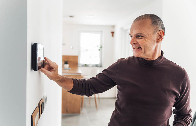 A man changes his thermostat during the winter.