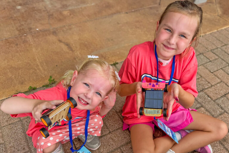 Photo of two girls showing their solar derby cars