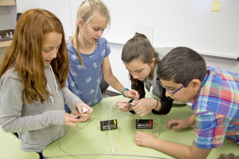 Kids huddled around table working on circuits