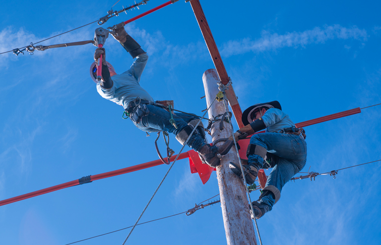 Photo thumbnail of linemen on pole at rodeo.