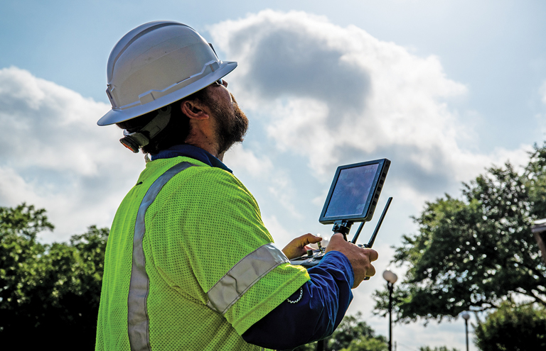 Photo of drone operator looking up at drone.